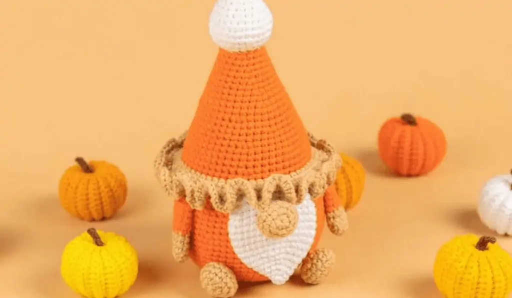 crochet pumpkin pie gnome with little pumpkins in the background