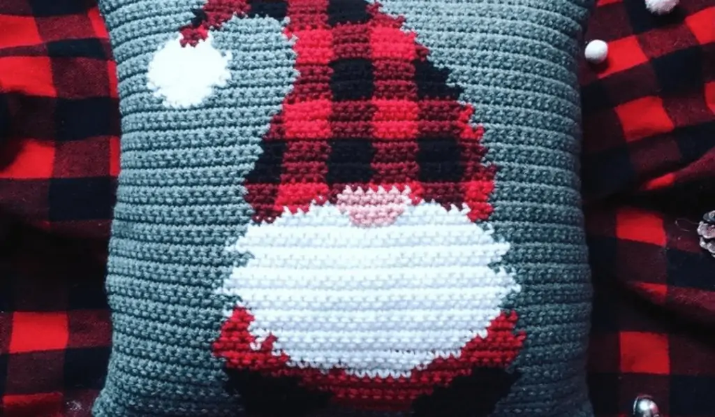 grey crochet pillow with a buffalo check gnome on it