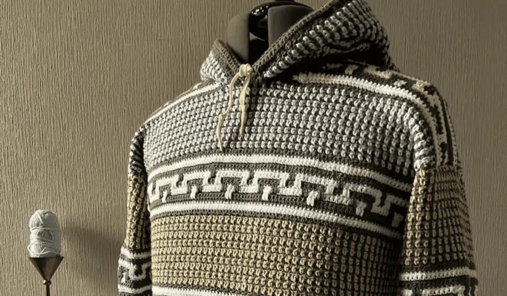 A crochet hoodie with many different line designs on it.