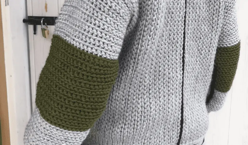 A grey crochet wear with a blck line going down the center and green elbow pads.