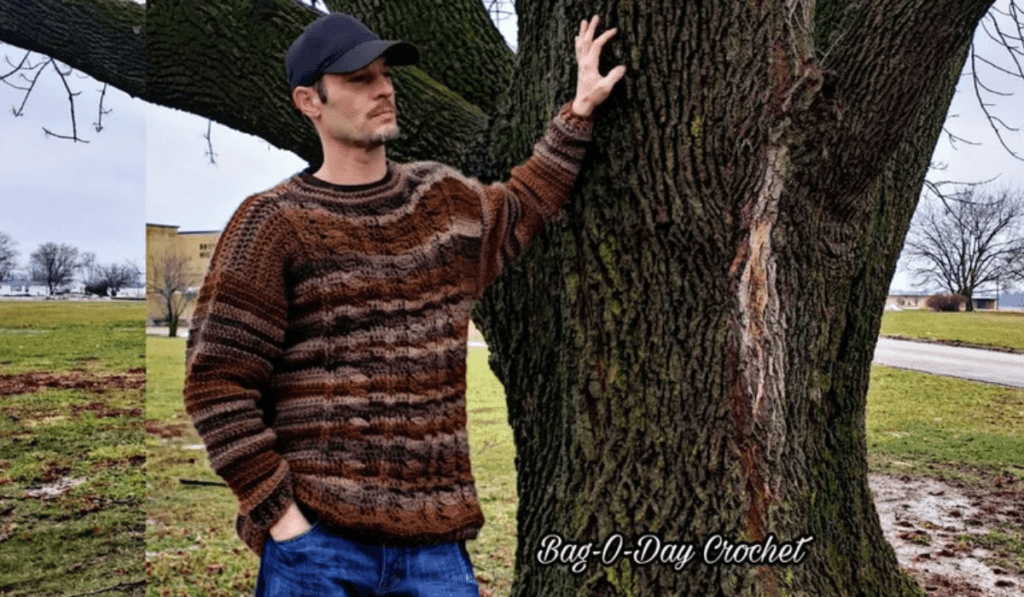 A man wearing a retro crochet sweater with varying shades of brown in it.