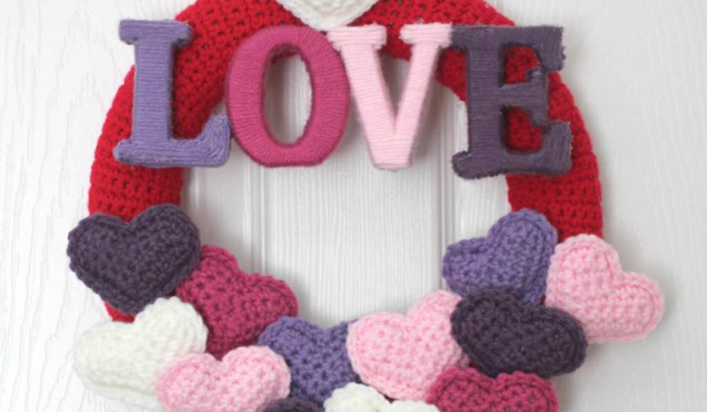 A crochet wreath with the word love and a bunch of little hearts along the bottom.
