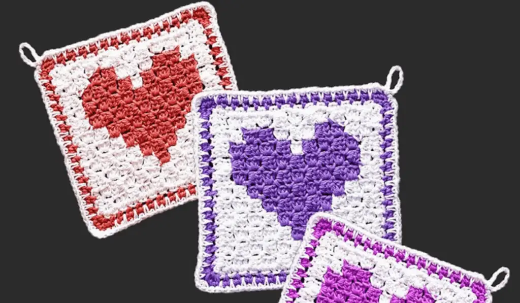 Three crochet heart dishclothes in red, purple, and fushia.