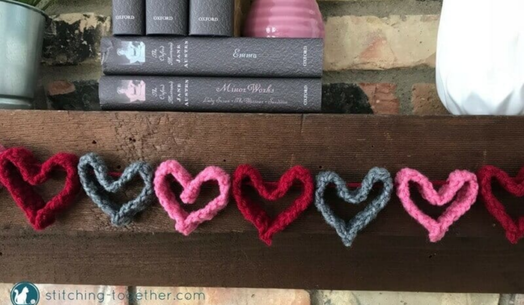 A crochet heart garland in red, grey, and pink.