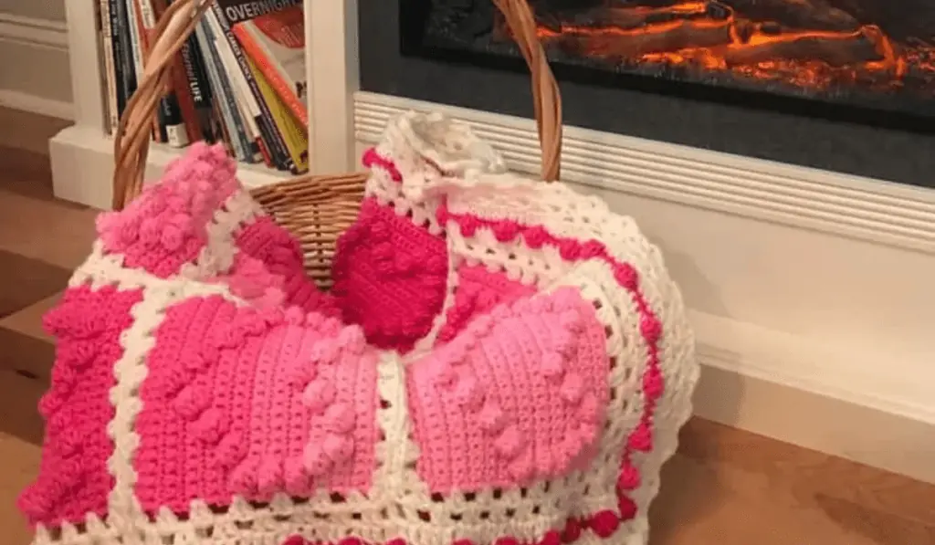 A afghan with pink gardient heart squares and a white boarder.