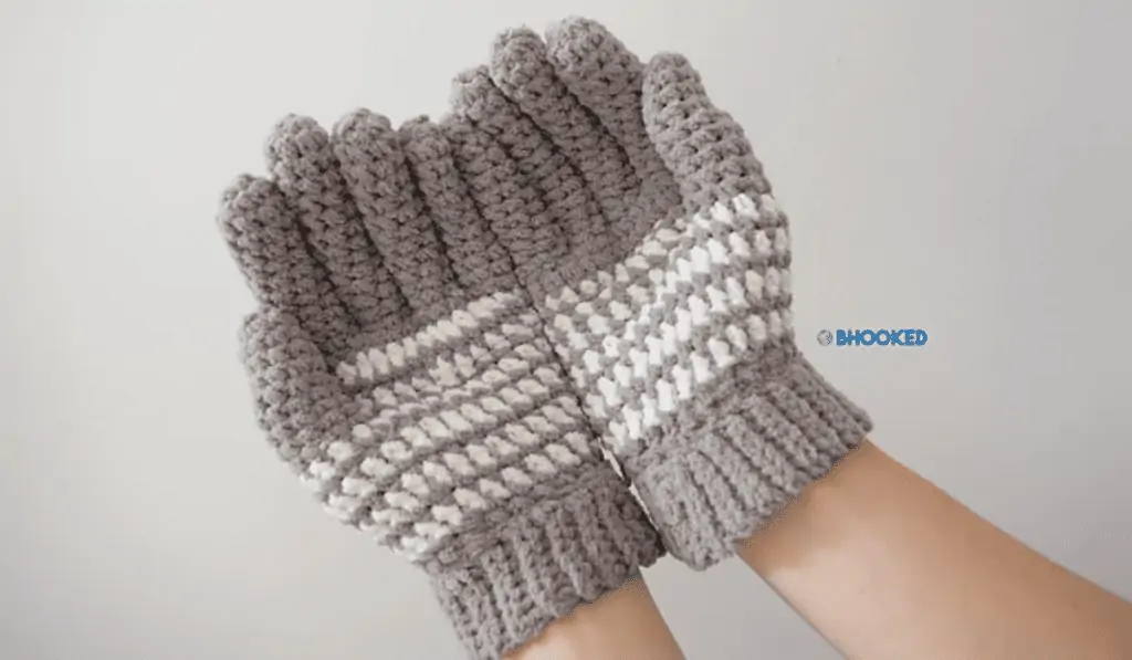 Grey crochet gloves with multiple white stripes going along the palm.