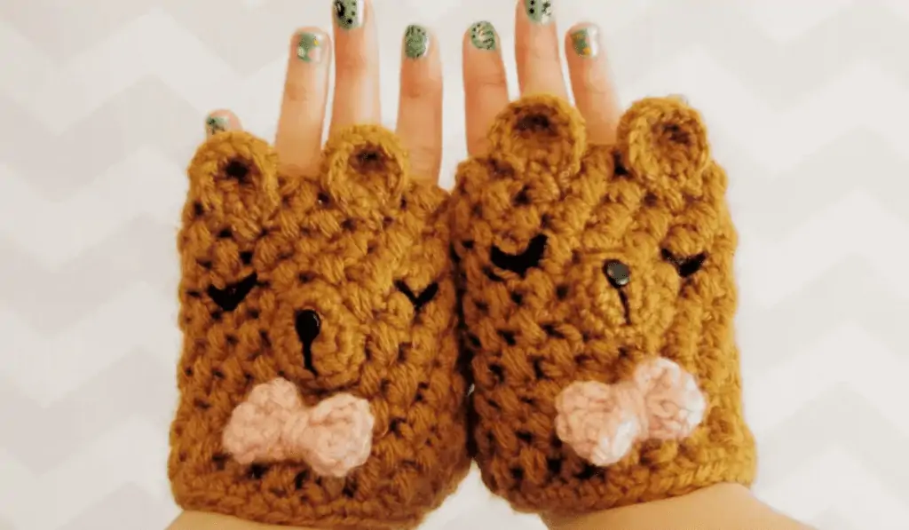 Crochet fingerless mittens that look like bears with pink bowties.