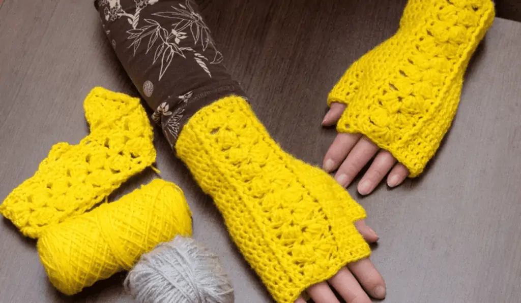 Yellow crochet fingerless gloves with a thumb hole.