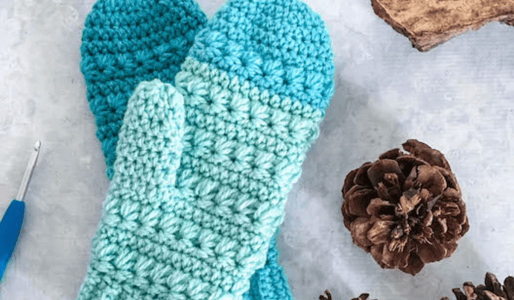 Crochet mittens that are ombre blue on one mitten and solid blue on the other.