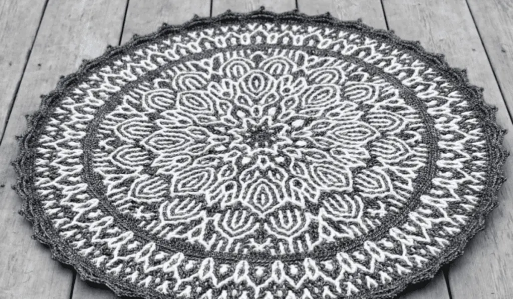 A circular white and grey rug that as a line art-style flower design.