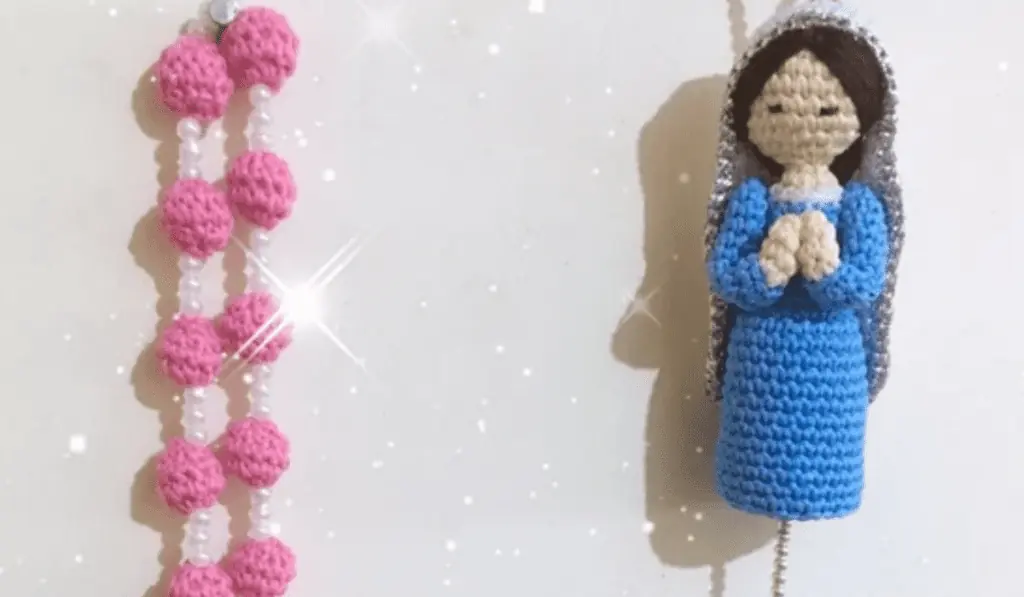 Two wall rosaries, one that is pink and one that is blue with an amigurumi of Mary.