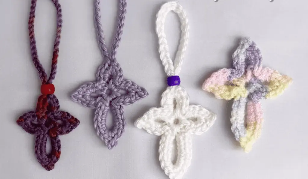 Four small crochet crosses in dark purple, light purple, white, and a mulitcolored pastel yarn.