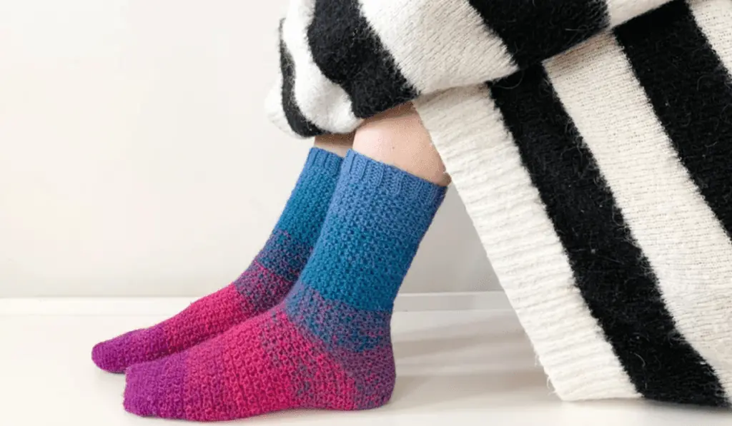 Crochet socks in blocks of color, purple, pink, to blue.