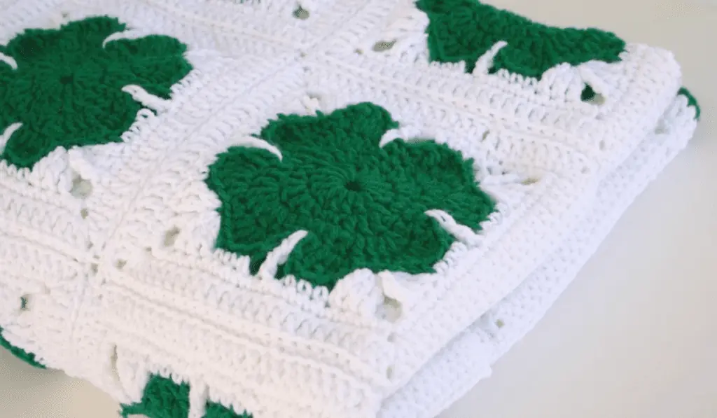 An all white afghan with four-leaf clover granny squares.