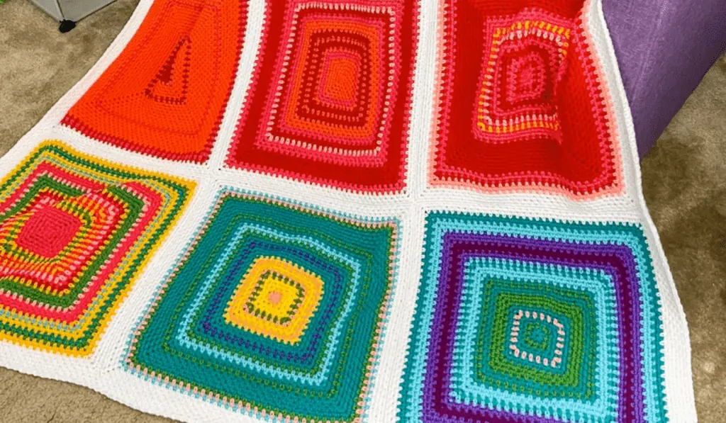 A crochet blanket with large squares in different colors.