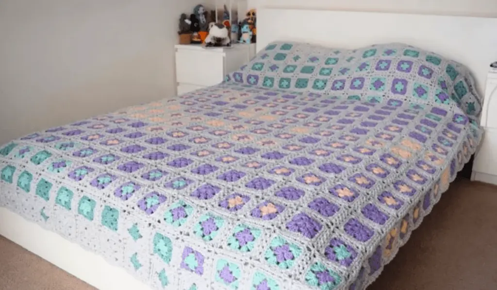 A blue, purple, and pink crochet blanket with squares of colors.