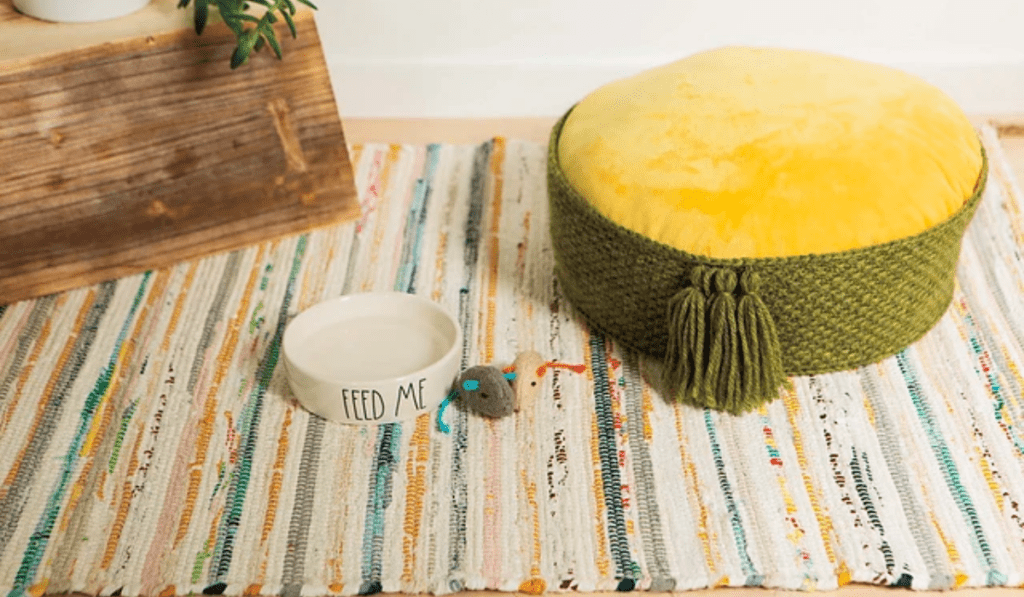 A green crochet cat bed with a yellow cushion inside the bed.