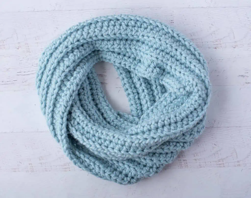 Blue ribbed crochet scarf placed in a circle