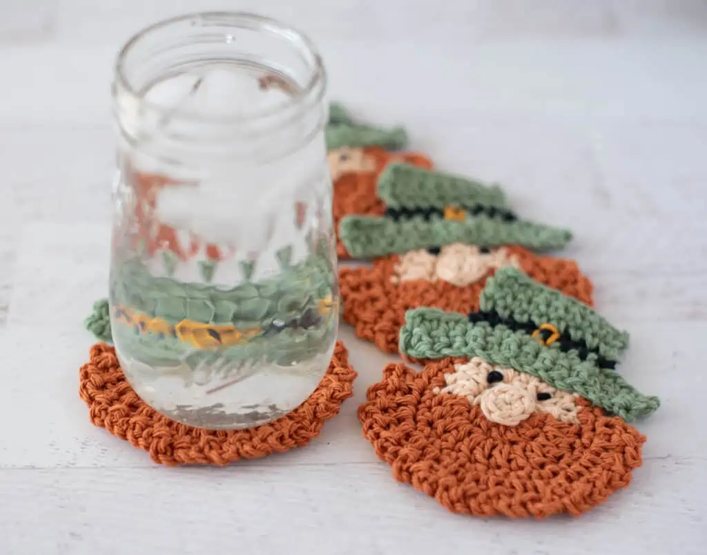 St Patricks Day Crochet Coasters, 4 leprechaun crochet coasters in a spiral with a glass of water