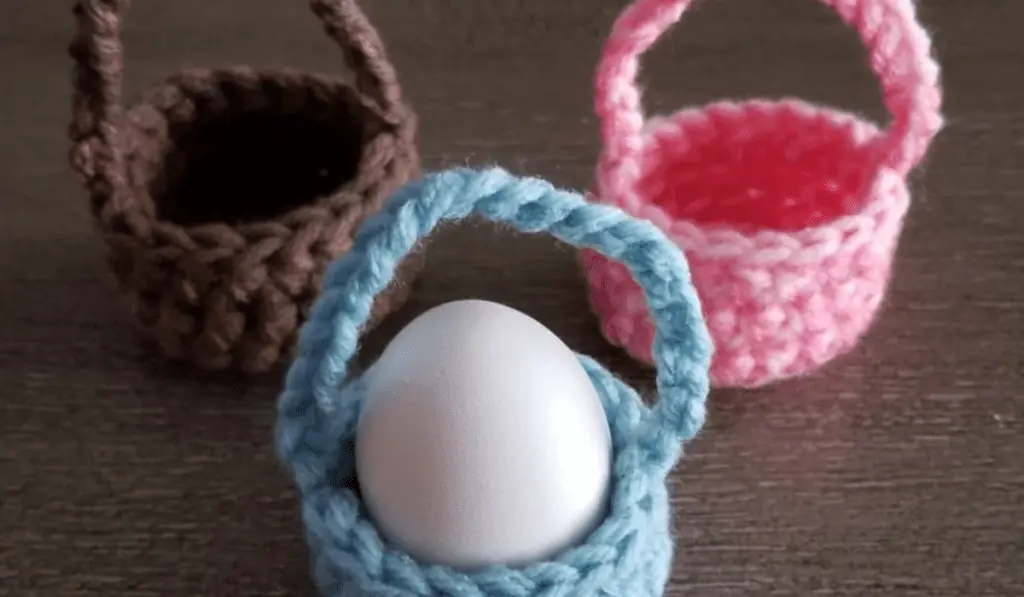 Mini crochet baskets that only fit one egg in blue, pink, and brown.