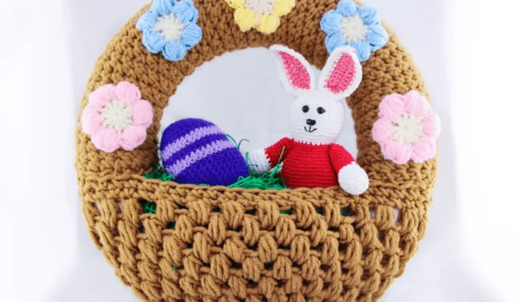 A crochet wreath that looks like an Easter basket with a amigurumi bunny in the basket.
