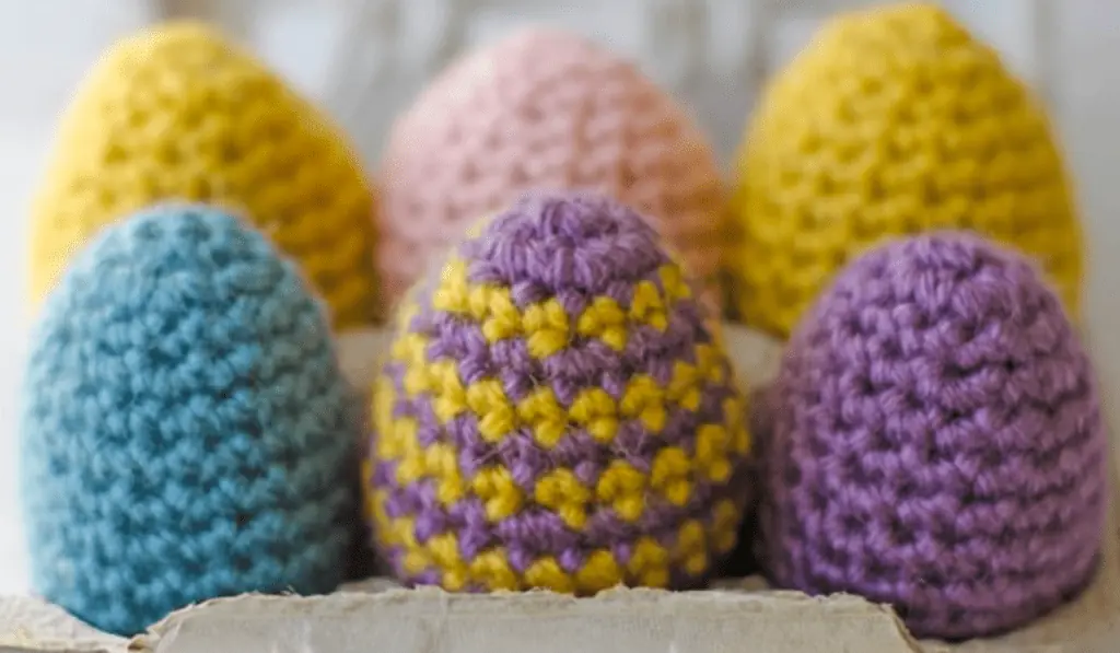 six crochet eggs in a carton.