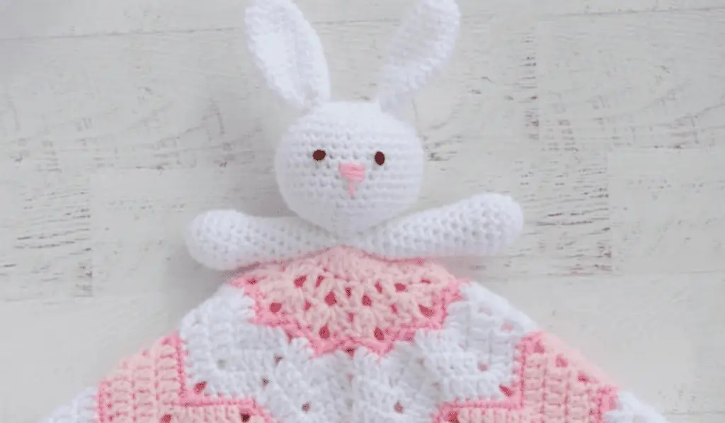 A bunny crochet lovey with a pink and white blanket
