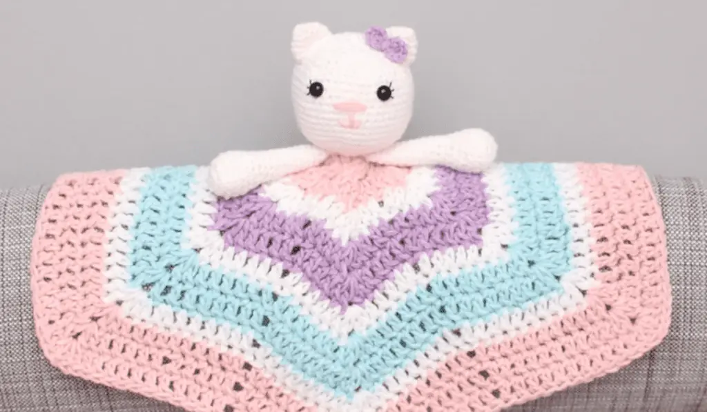 A kitty crochet lovey with pink, blue, purple, and white yarn to make up the blanket.