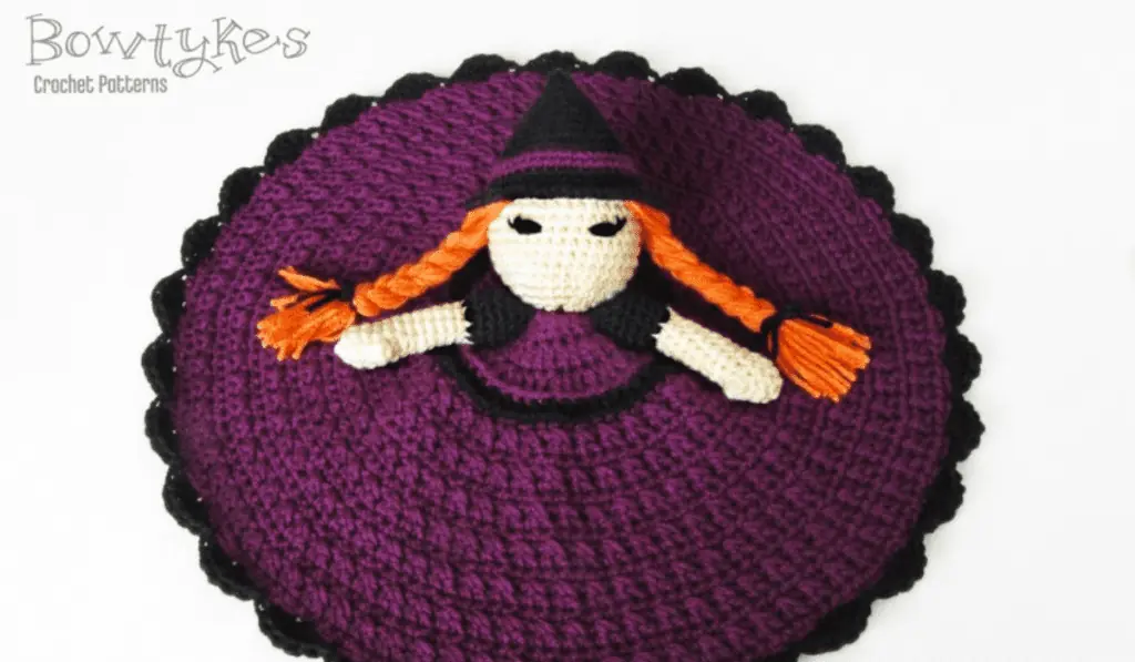 A crochet witch lovey with a purple blanket dress.
