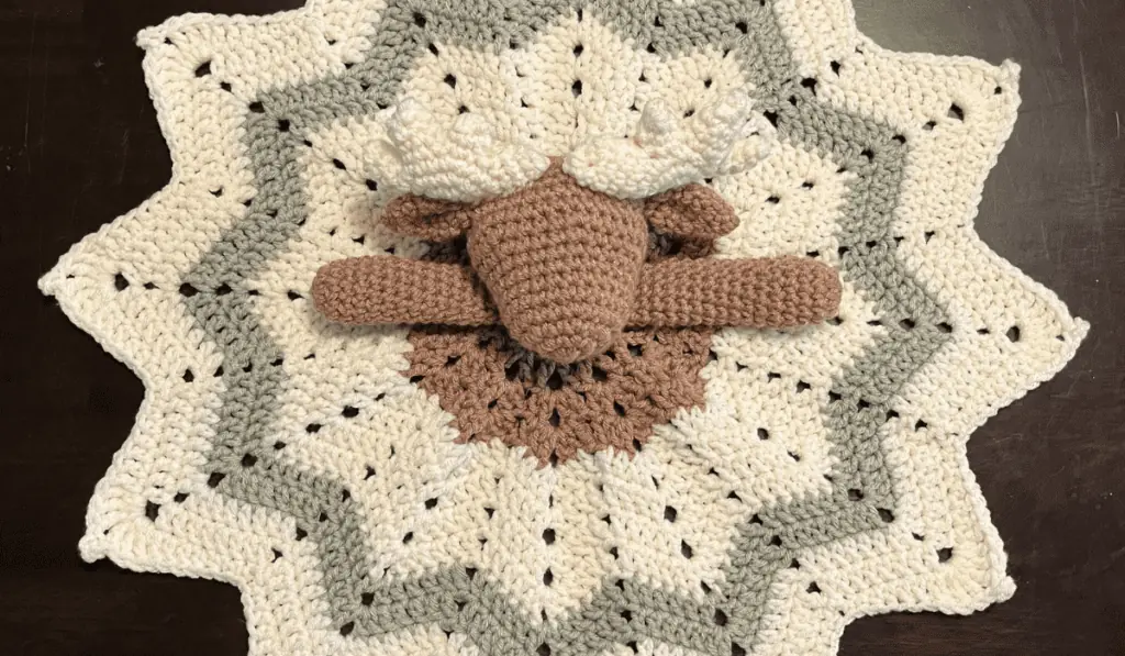 A crochet lovey moose with brown, white, and green yarn.