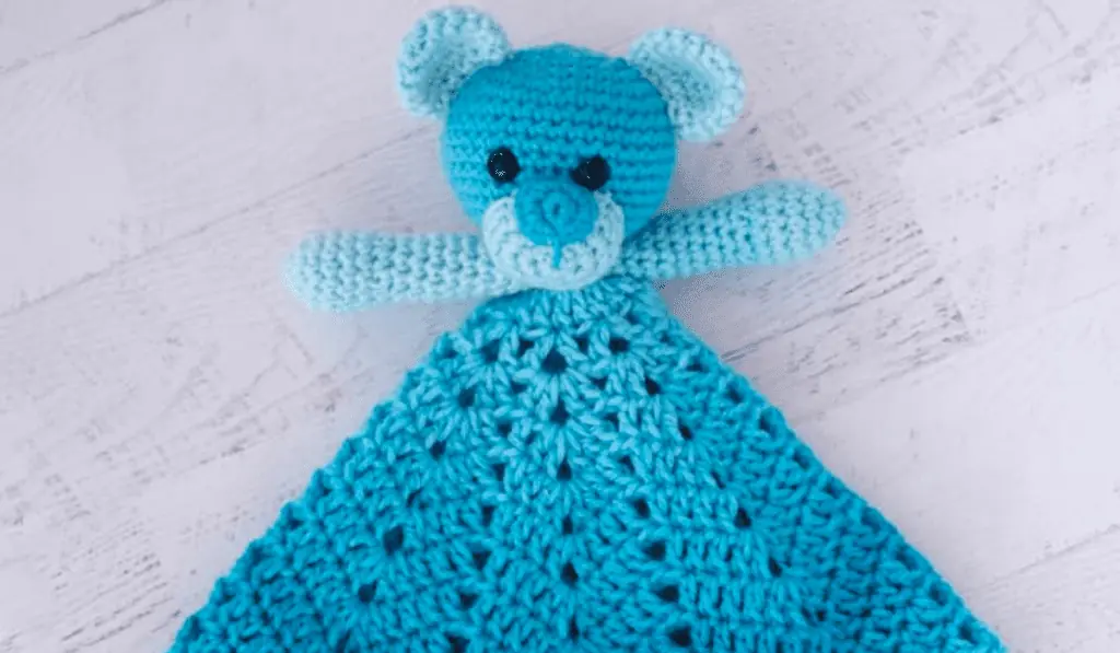 A crochet bear lovey made from blue yarn.