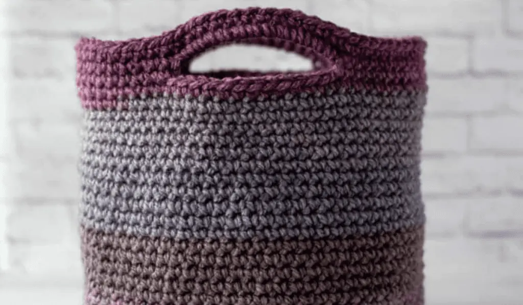 A crochet basket tote with purple and blue colored yarn.