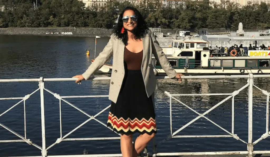 A woman wearing a crochet skirt in front of a boat.