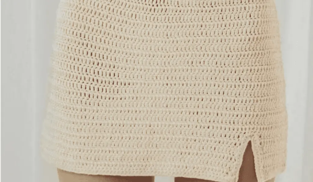 A white crochet mini skirt with a small slit