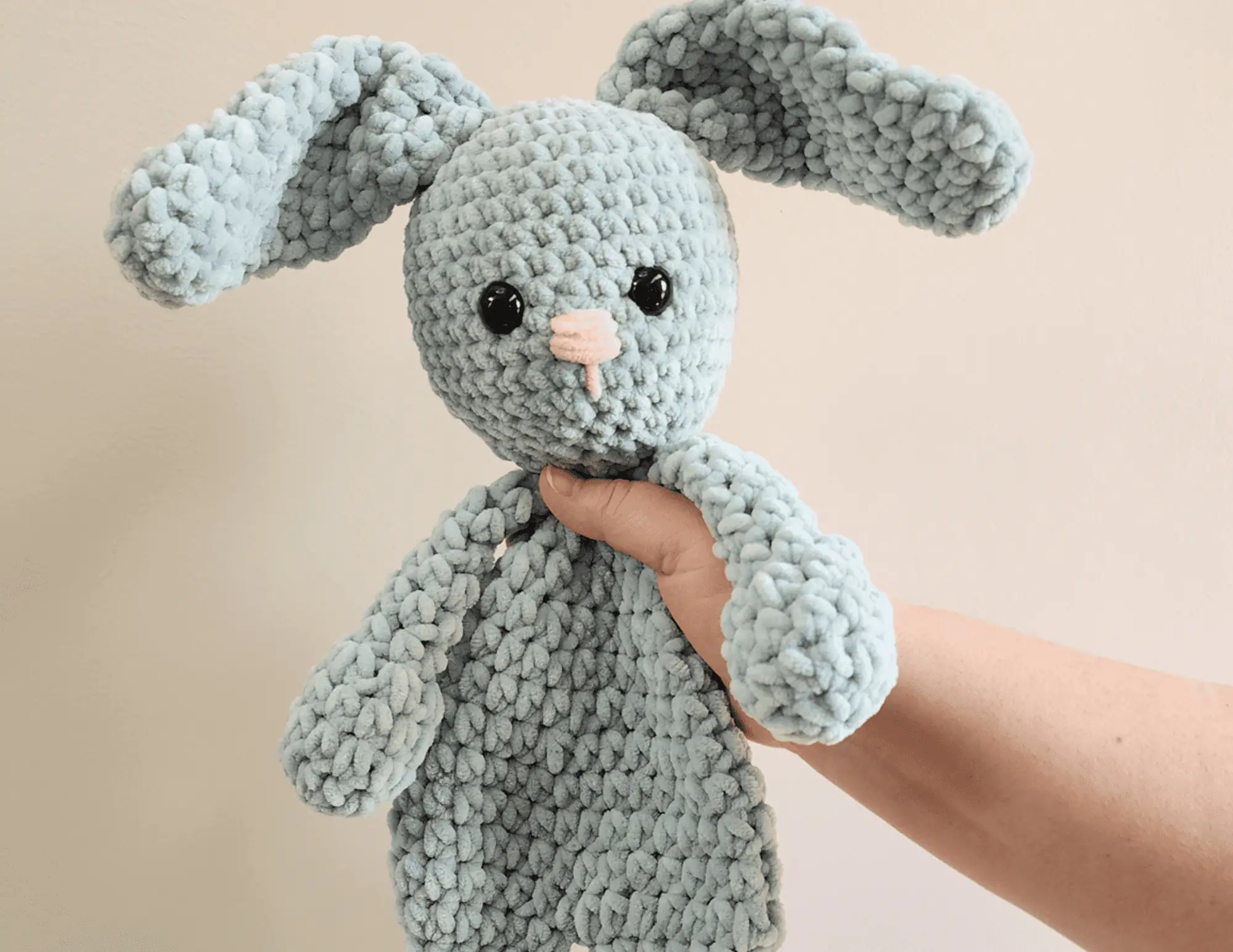 blue bunny crochet snuggler held up against a wall