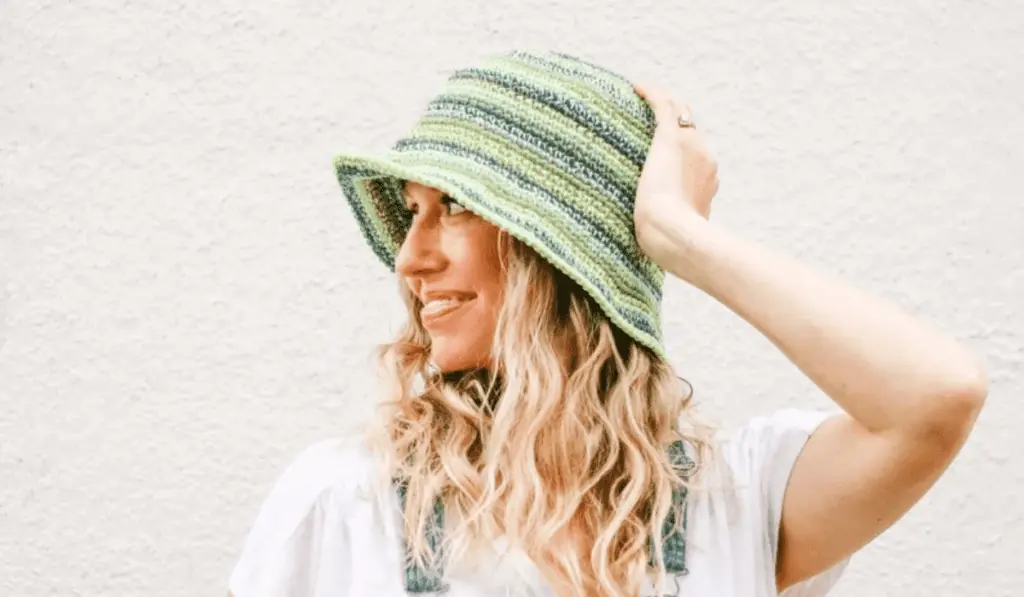A crochet bucket hat that features different rows of green yarn.