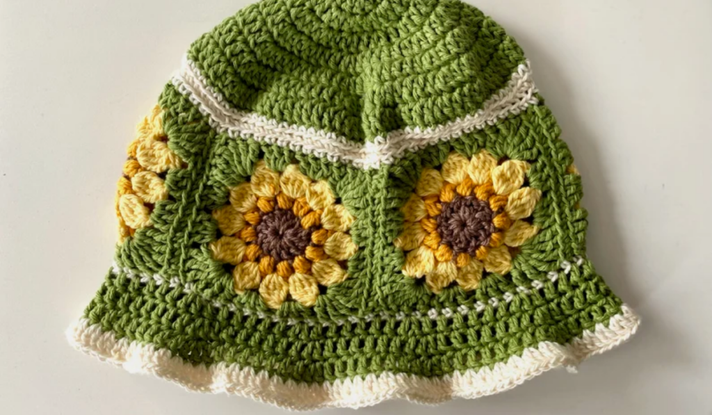 A green crochet bucket hat with granny square sunflowers around the side.