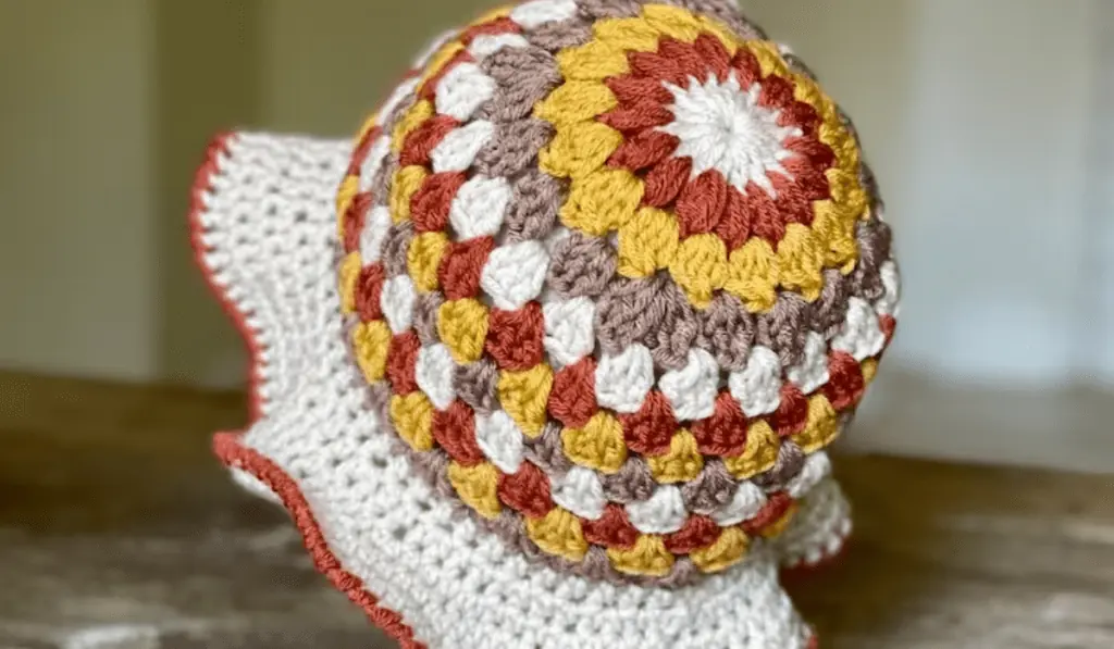 A sunburst crochet bucket hat with a white brim and a red edge around the brim.