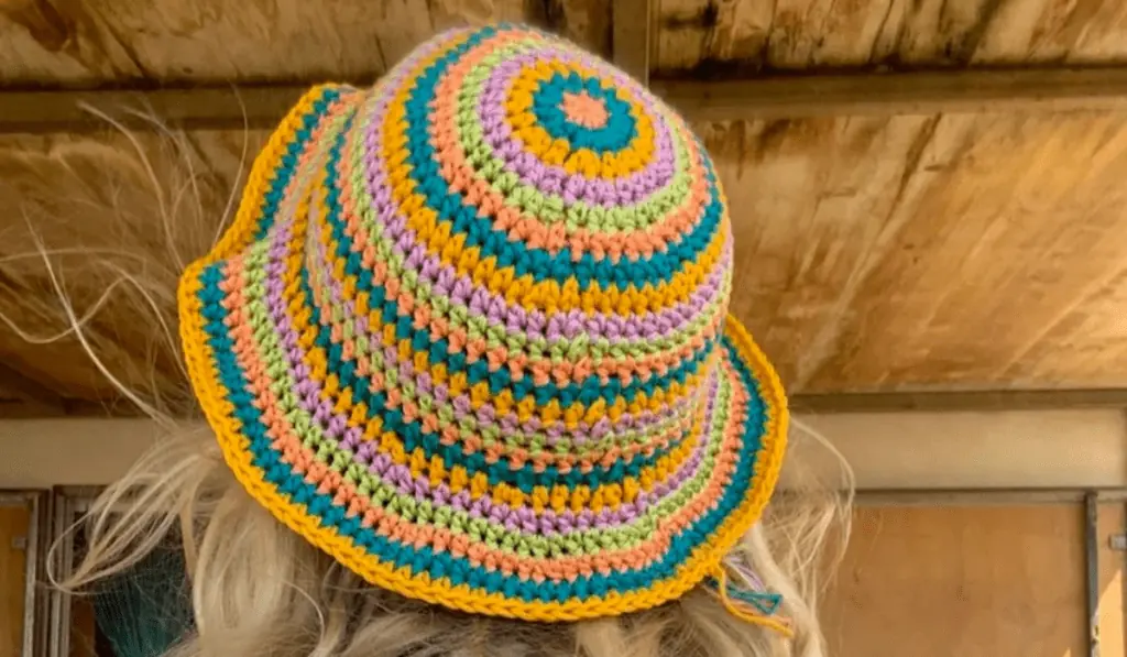 A crochet bucket hat with rows of different colors including pink, blue, orange, purple, and green.