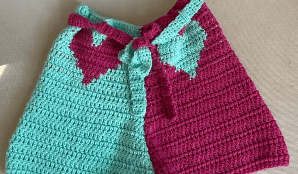 A pair of crochet shorts with light blue on one side and hot pink on the other. A heart is on each side in the opposing color.