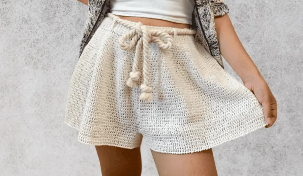 Flowy crochet shorts that are off-white and has a rope going through the belt holes.