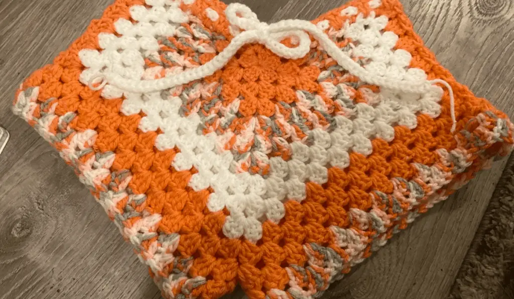 Crochet booty shorts with rows of orange and white yarn and a white drawstring
