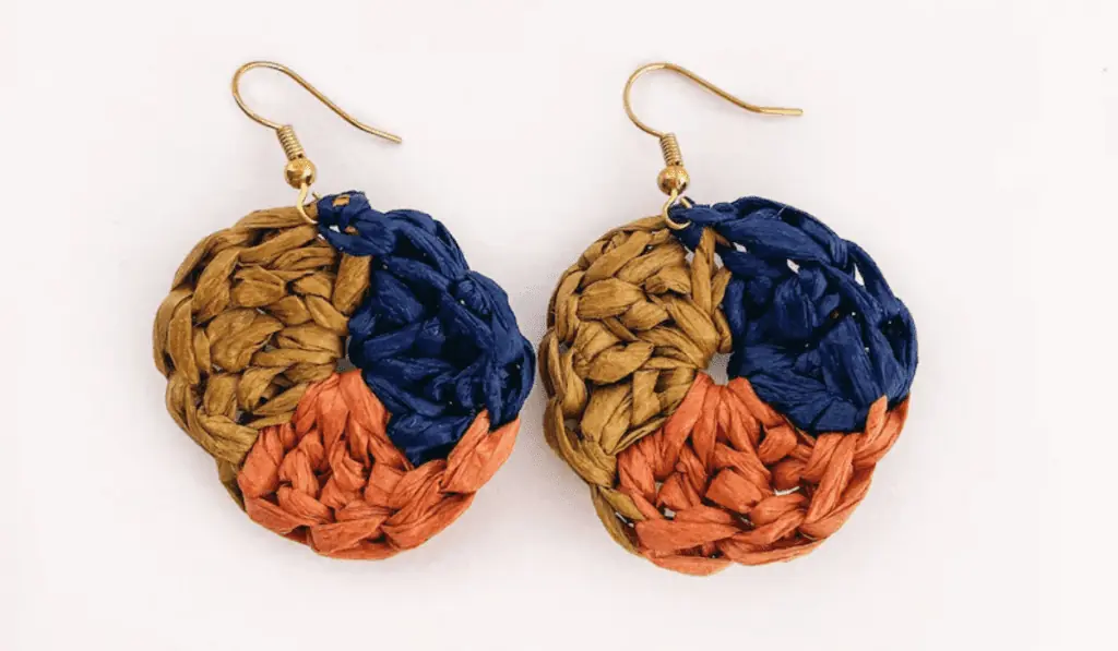 An earring crochet pattern with three colors separated in thirds. The colors are a gold/beige, pink, and navy.