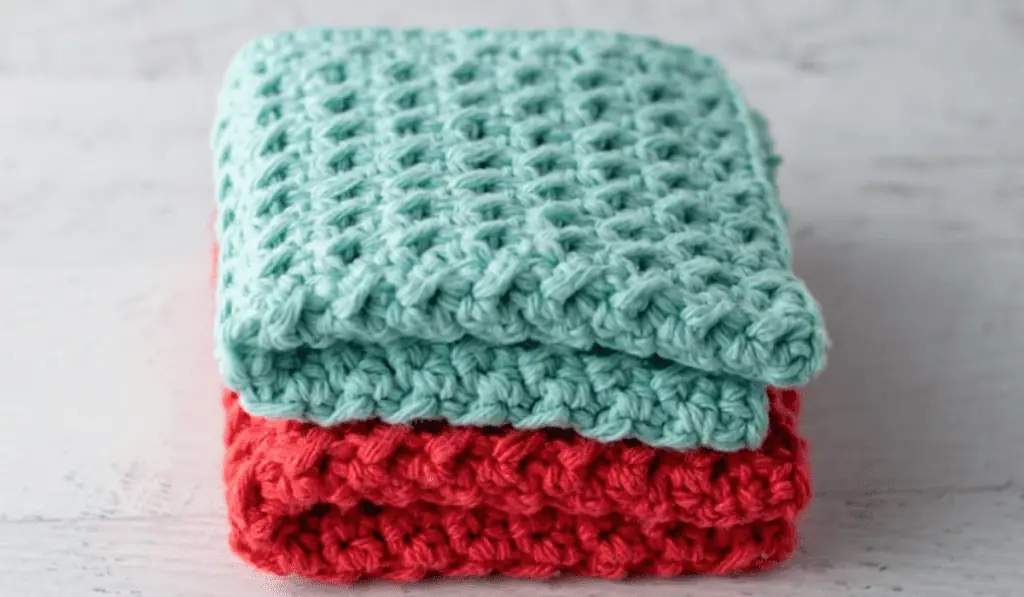 Two crochet dishcloths, one is blue and one is red.