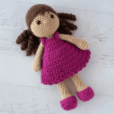 crochet doll with dark brown hair and pink dress