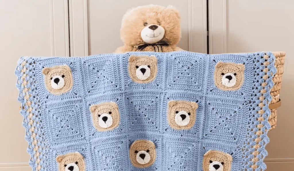A crochet baby blanket with little bears in a checkboard design.
