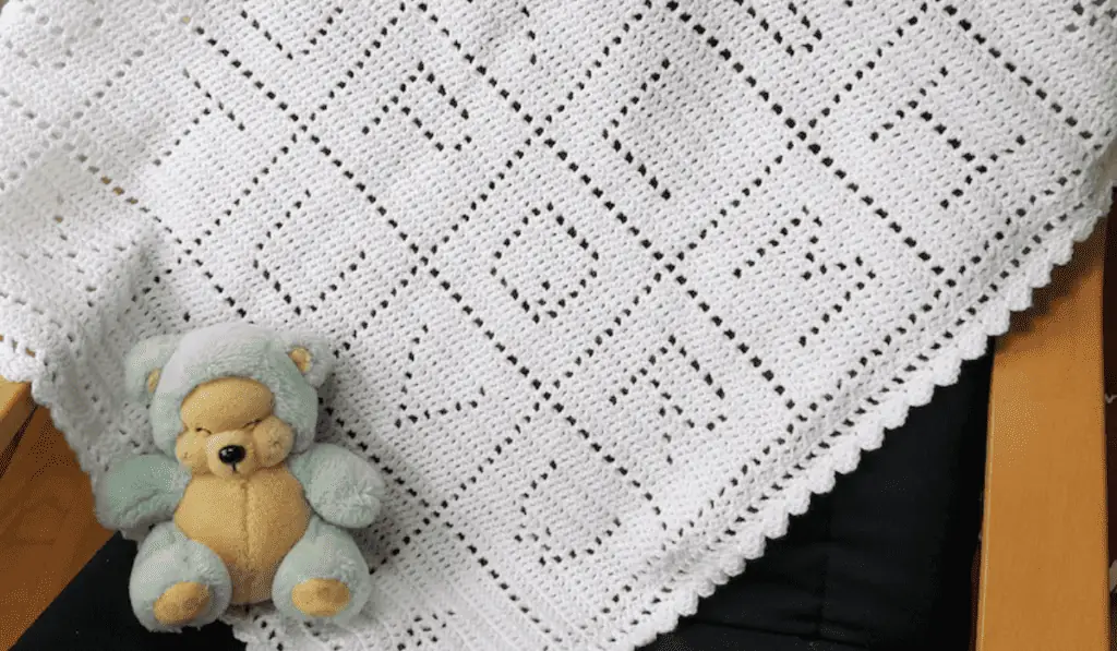 A white crochet blanket with each letter of the alphabet.