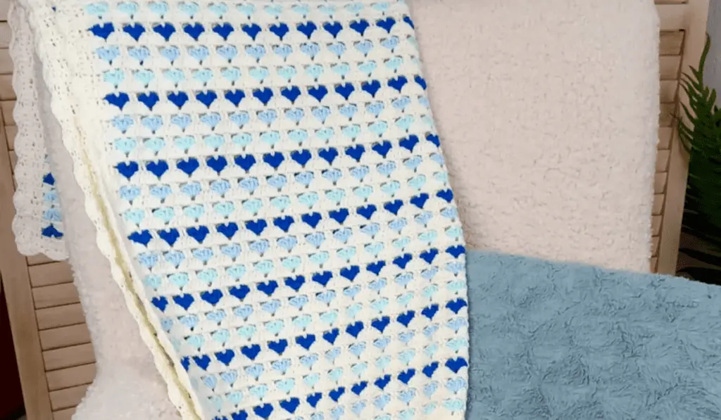 A crochet blanket featuring a variety of blue hearts.