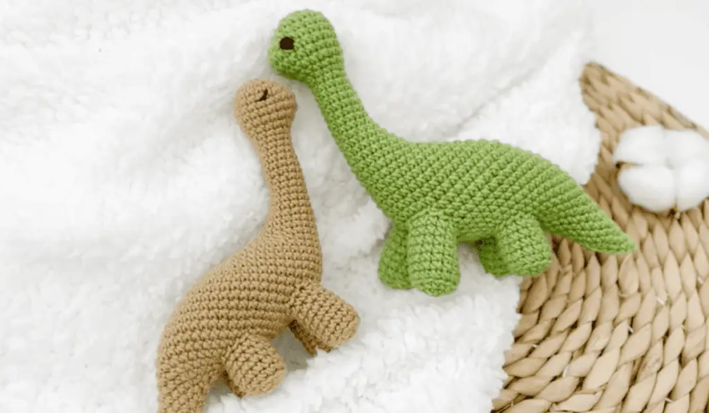 Two crochet dinosaurs, one in green and one in brown.