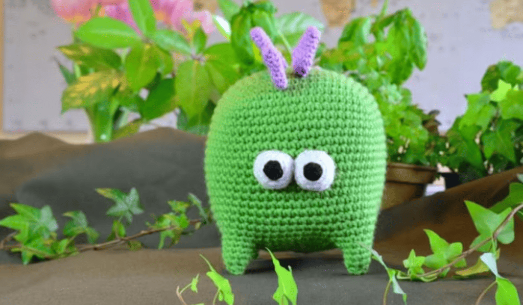 A square shaped crochet dinosaur with big googly eyes